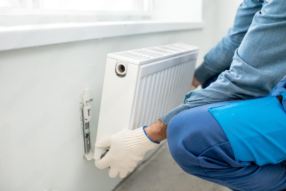 a man is installing a radiator on a wall .