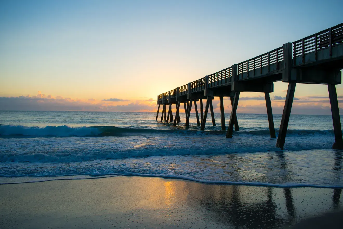 A pier leading into the ocean at sunset