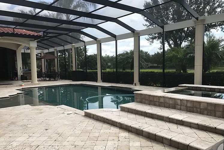 A swimming pool with a screened in area and steps leading to it.