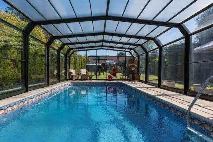 A large indoor swimming pool with a clear roof.