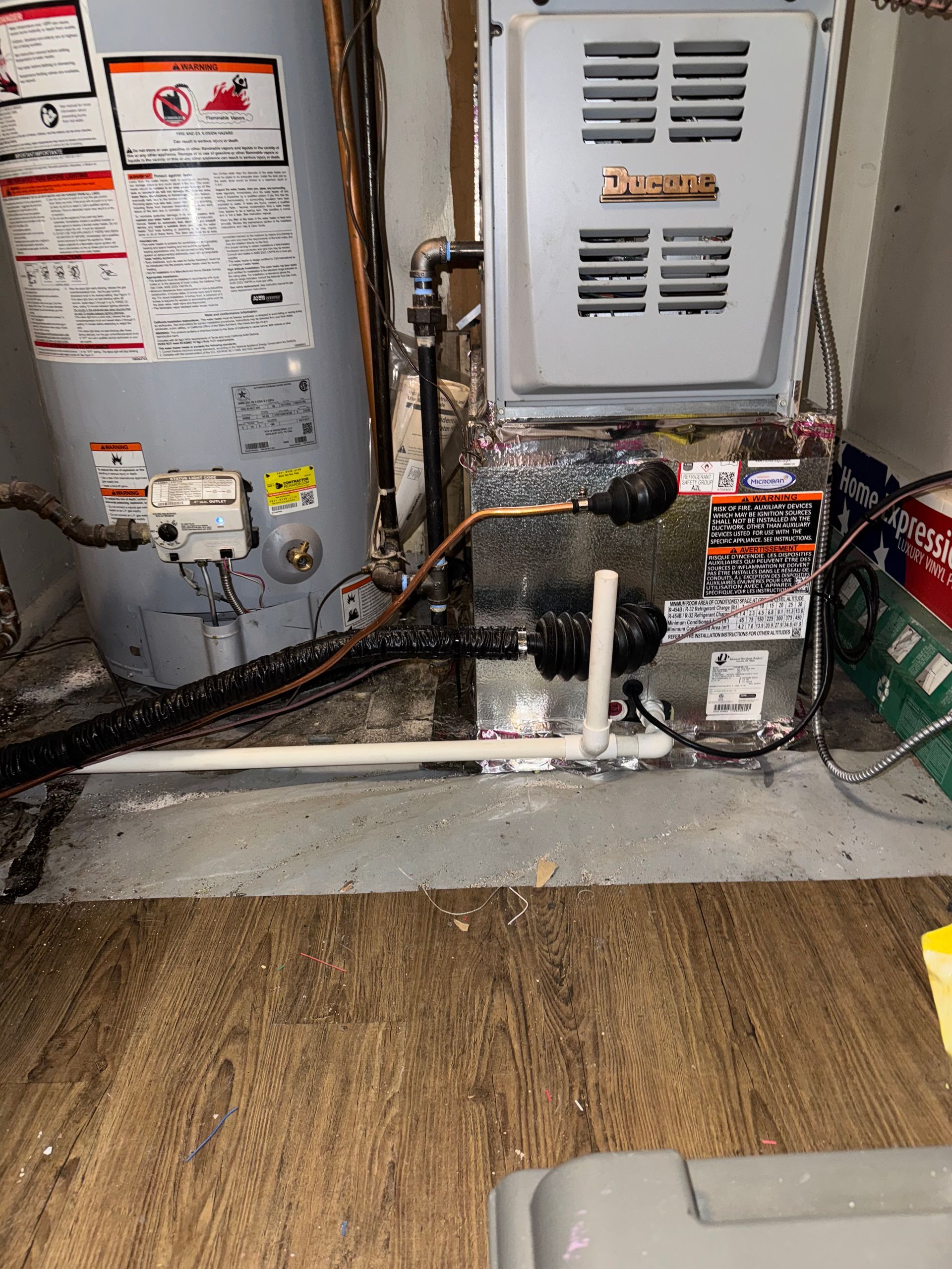 Water heater and furnace in a basement setting, with pipes and connections visible.