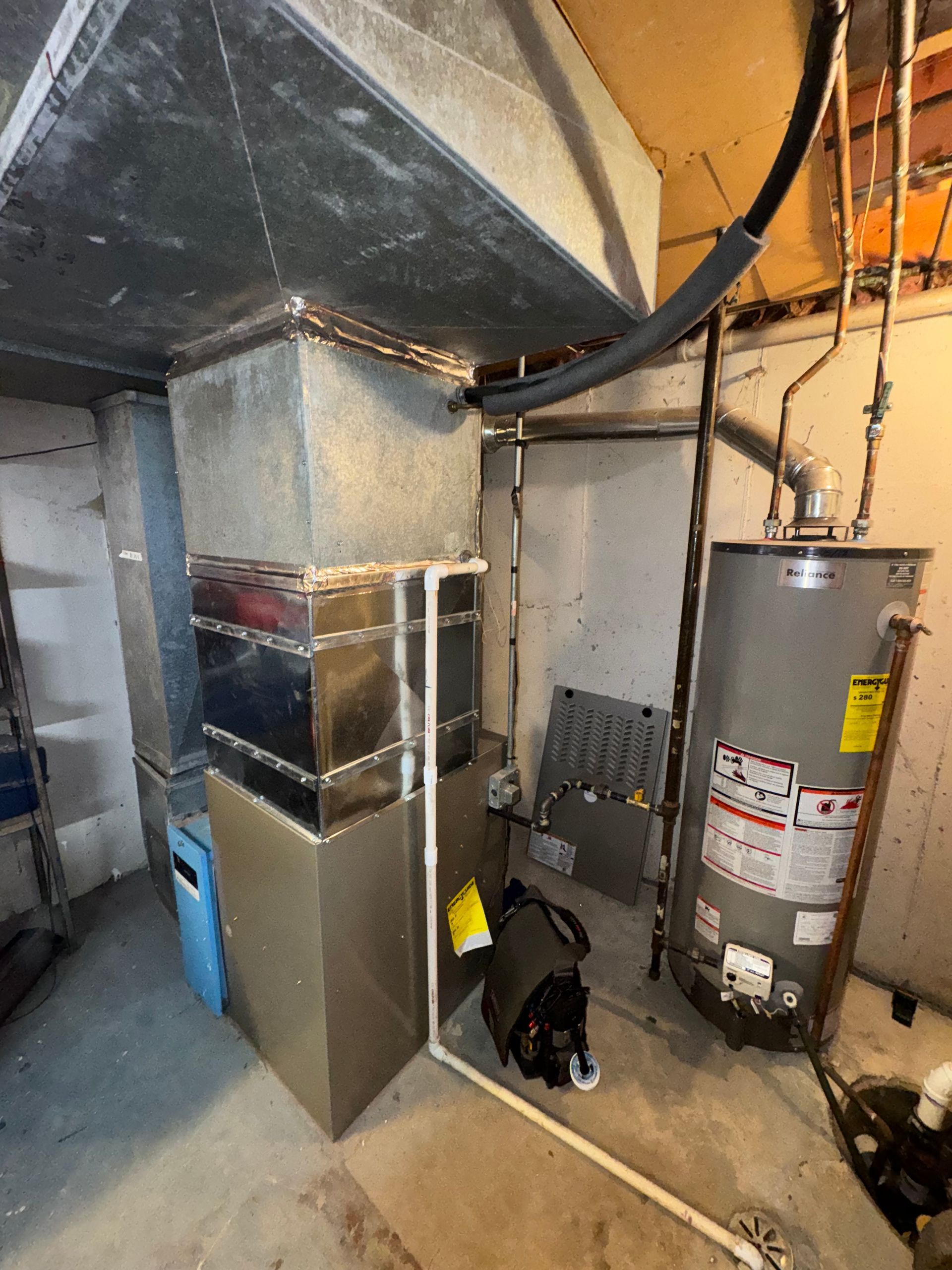 HVAC system with ductwork, water heater, and piping in a basement setting.