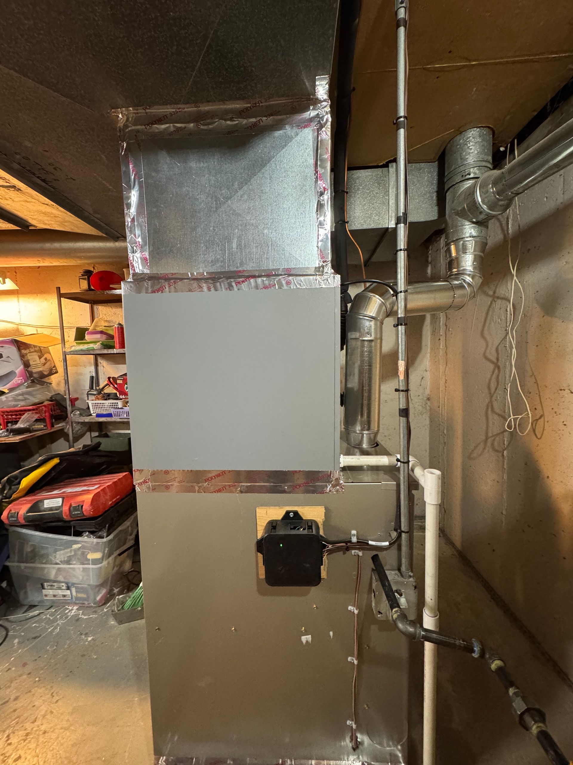 Furnace and ductwork in a basement. The furnace is metal, with connected pipes and wiring.