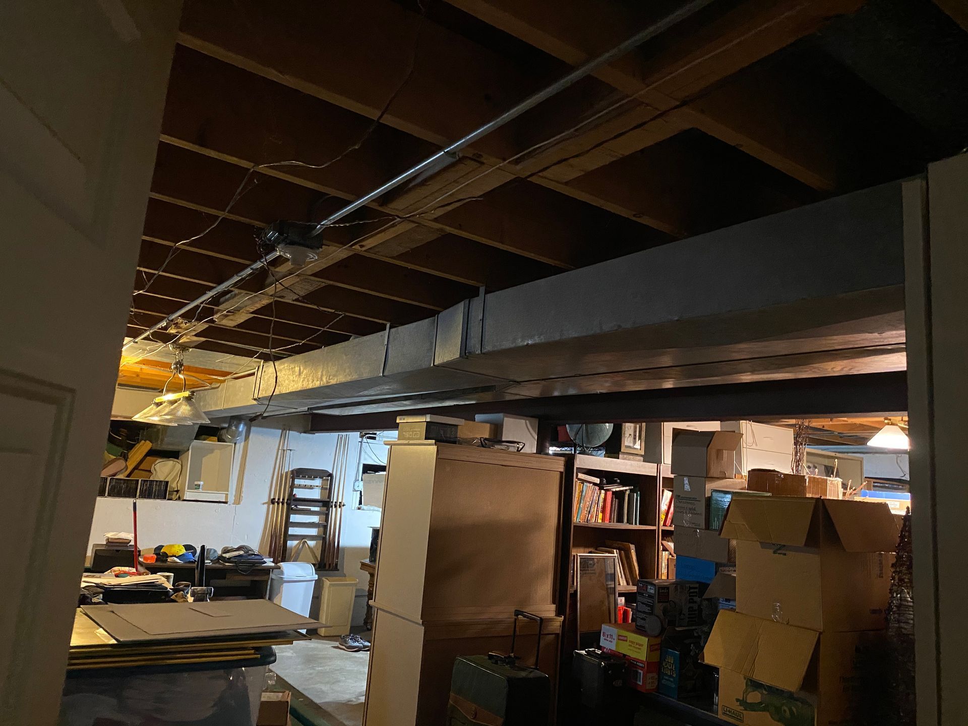 Basement with exposed ceiling joists, support beam, and clutter.