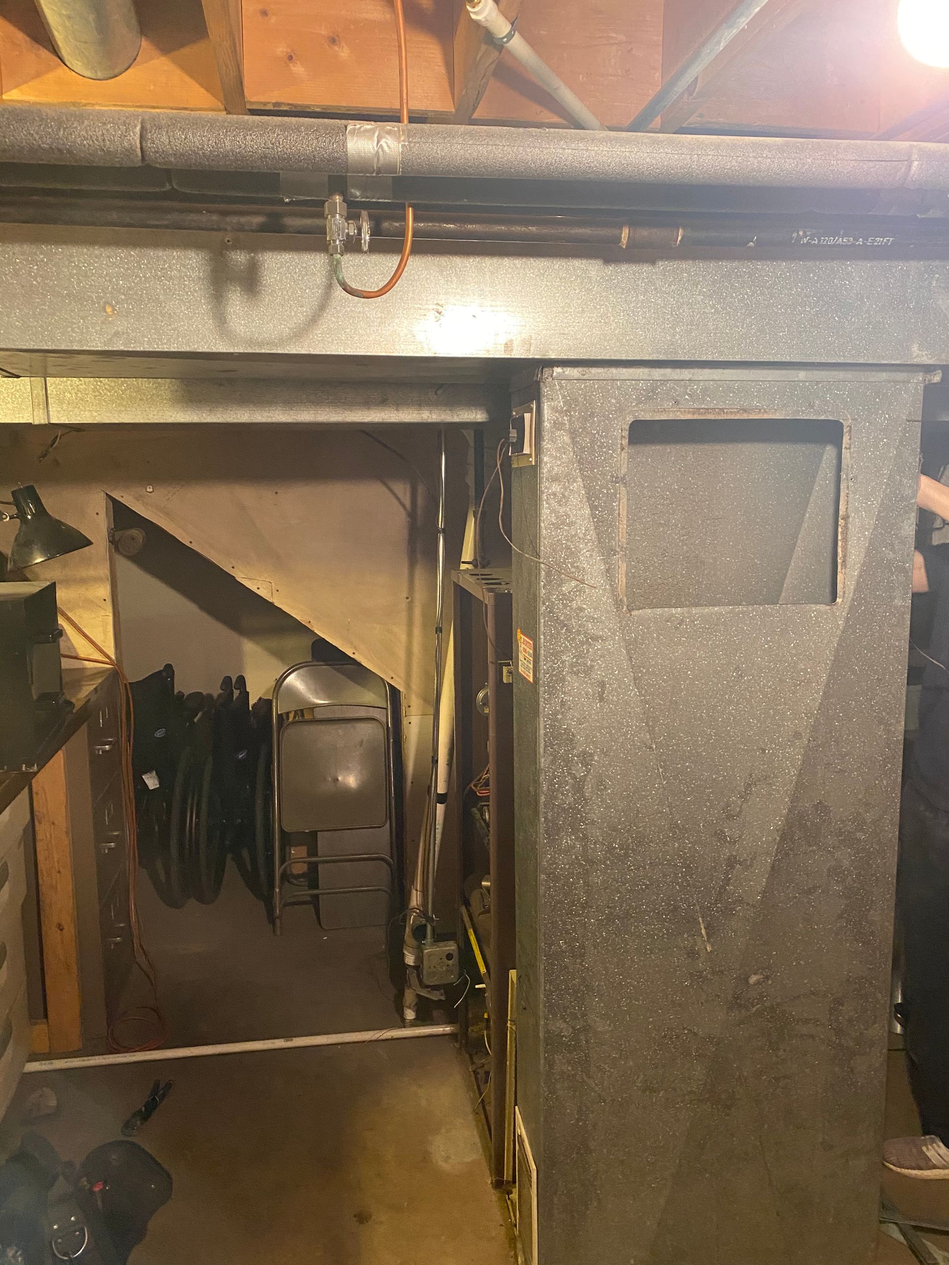 HVAC system in a basement. Ductwork and a large metal unit are visible.