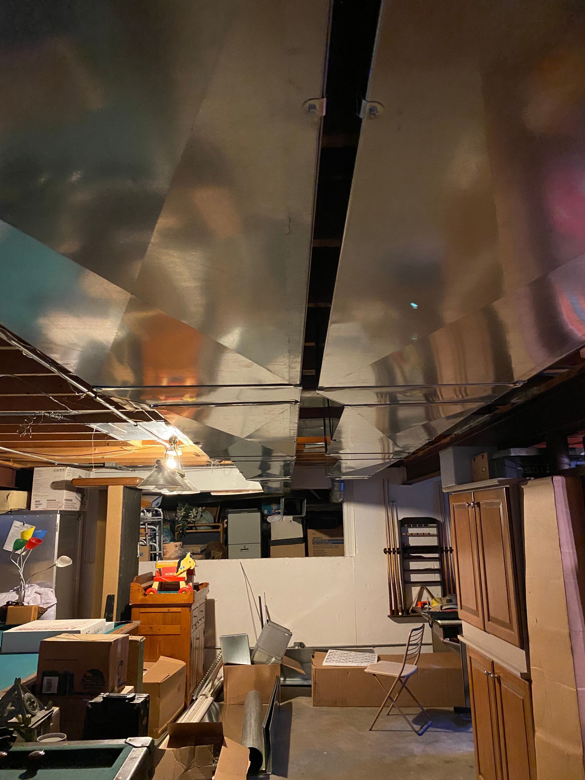 Basement interior with metal ceiling, ductwork, boxes, and miscellaneous items.