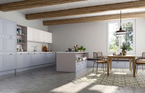 Una cocina con muebles blancos, vigas de madera, una mesa y sillas.