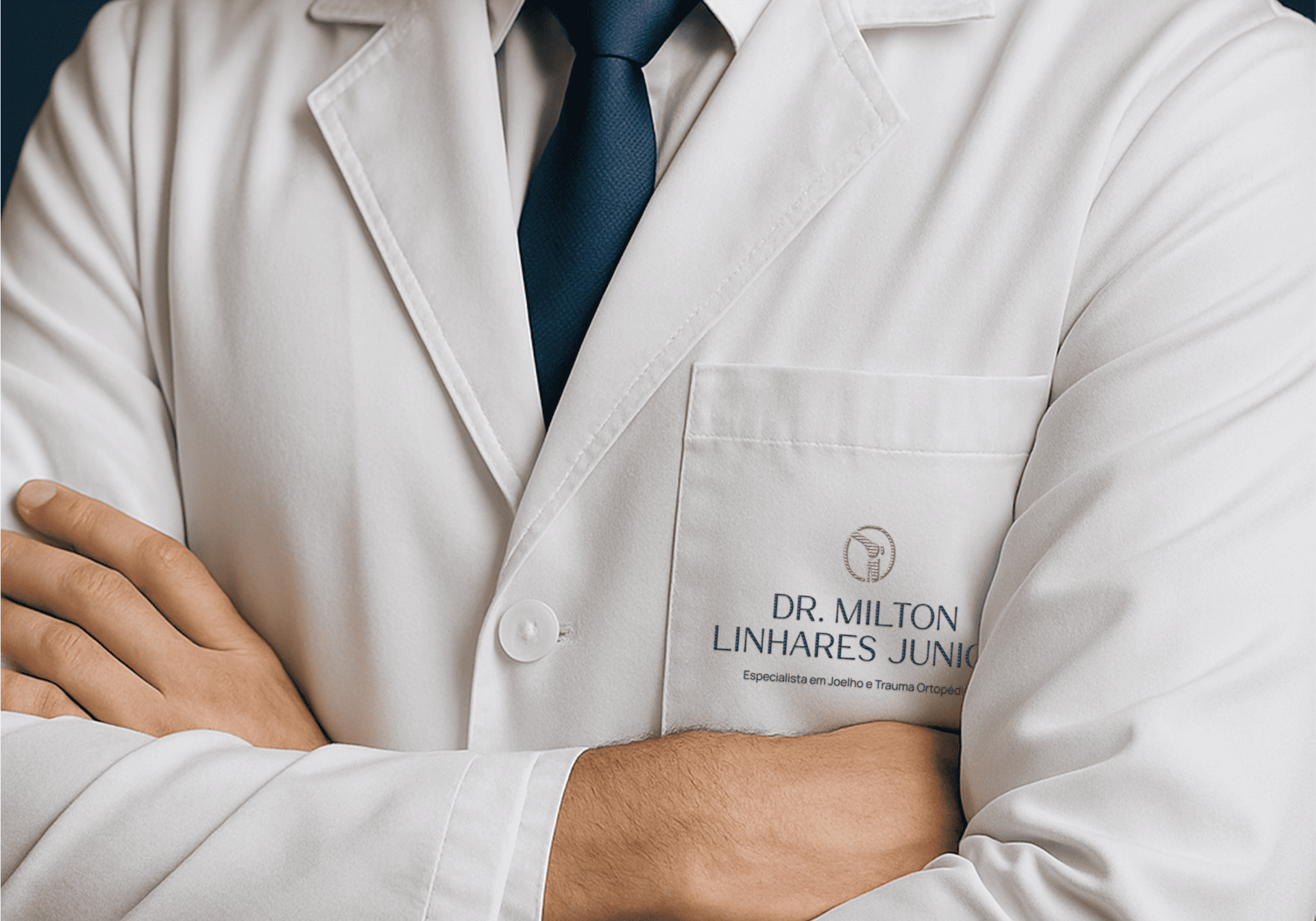 Médico de jaleco branco, com os braços cruzados e gravata azul.