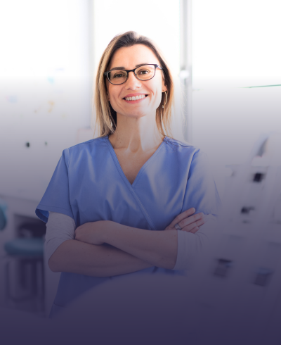 Uma enfermeira está sorrindo com os braços cruzados e usando óculos.