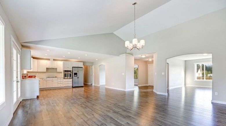 A large empty room with hardwood floors and a chandelier.