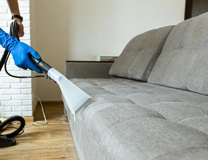 Man Steam Cleaning a Grey Lounge — Capital Pro Care in Gungahlin, ACT