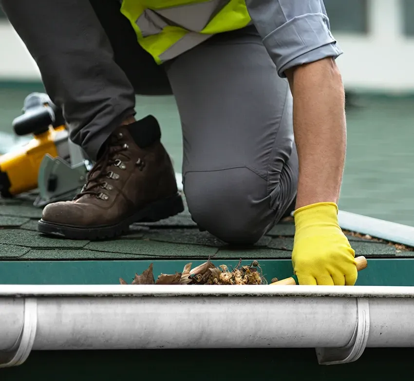 A Man Cleaning Out Leaves From A Gutter — Capital Pro Care in Gordon, ACT