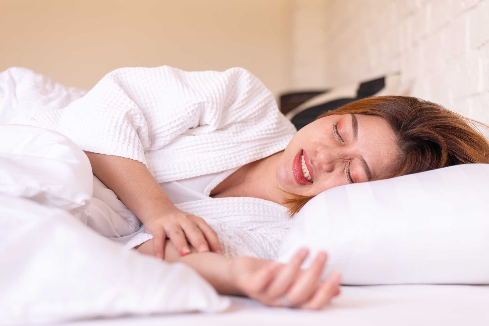 A woman is sleeping on a bed with white sheets and pillows.