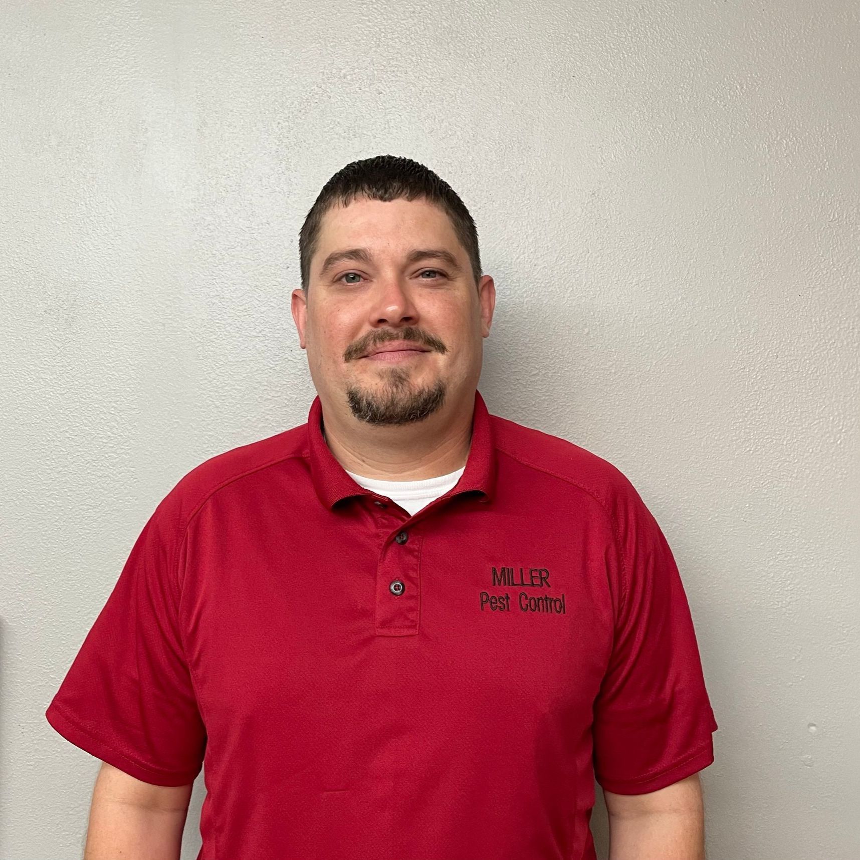 A man wearing a red shirt that says miller pest control