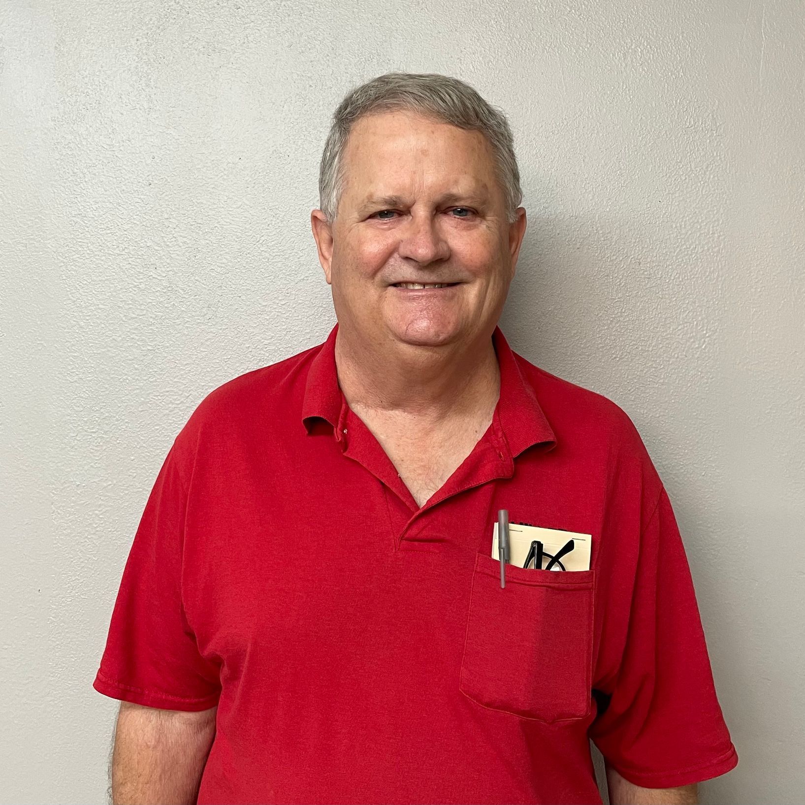 A man in a red shirt with a pen in his pocket.