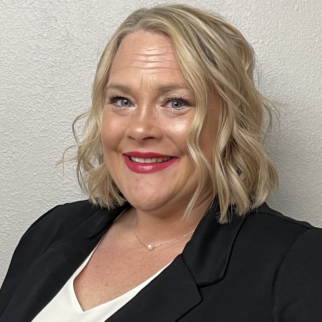 A woman in a black jacket and white shirt is smiling for the camera.