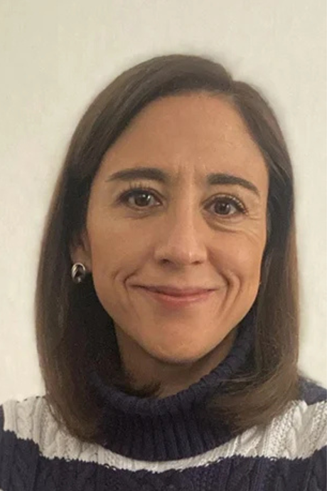 Mujer de cabello castaño sonriendo a la cámara, vistiendo un suéter de rayas azules y blancas.