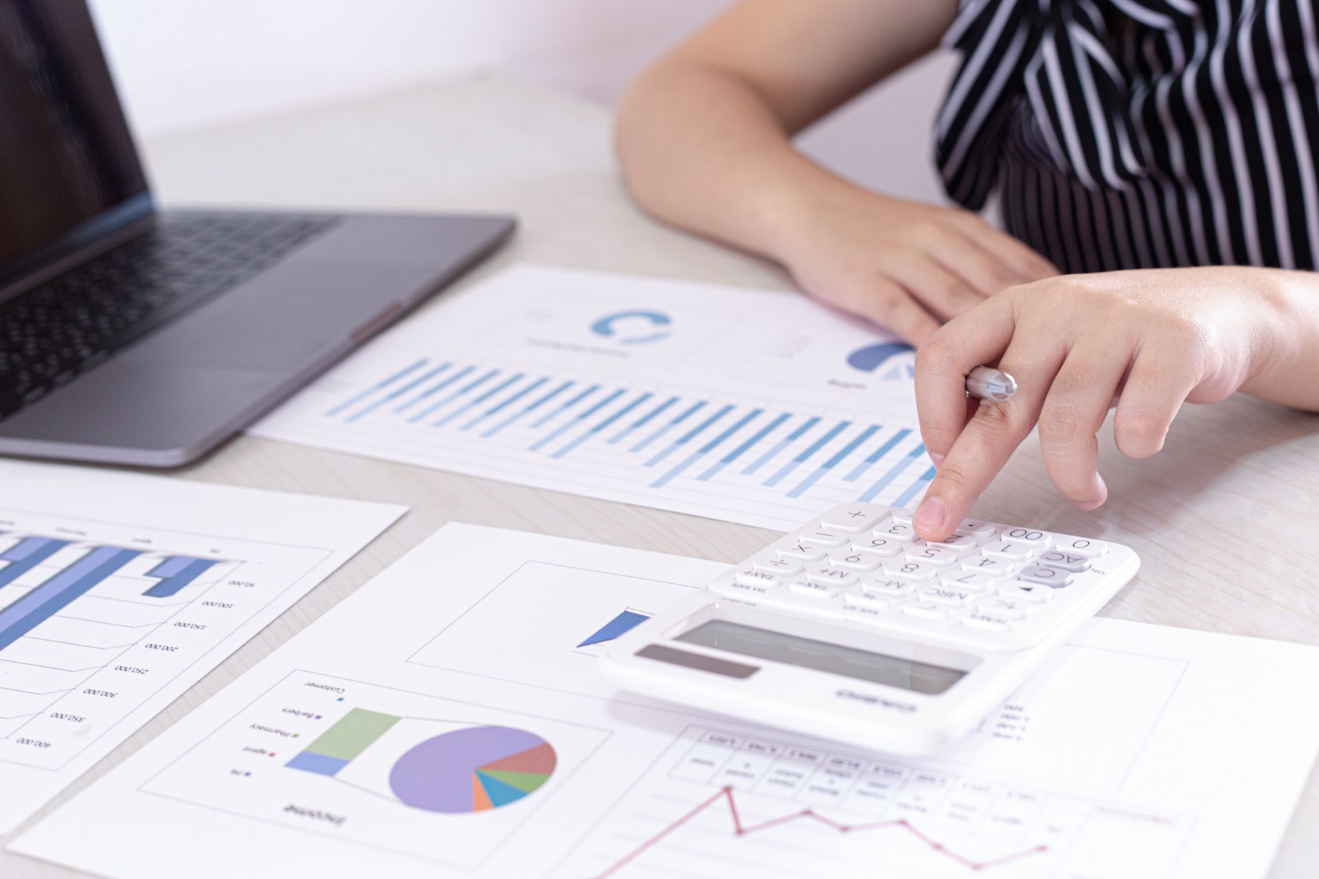A woman is sitting at a desk using a calculator.