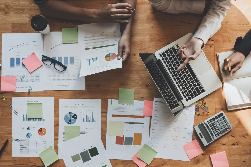 A group of people are sitting at a table with papers and a laptop.