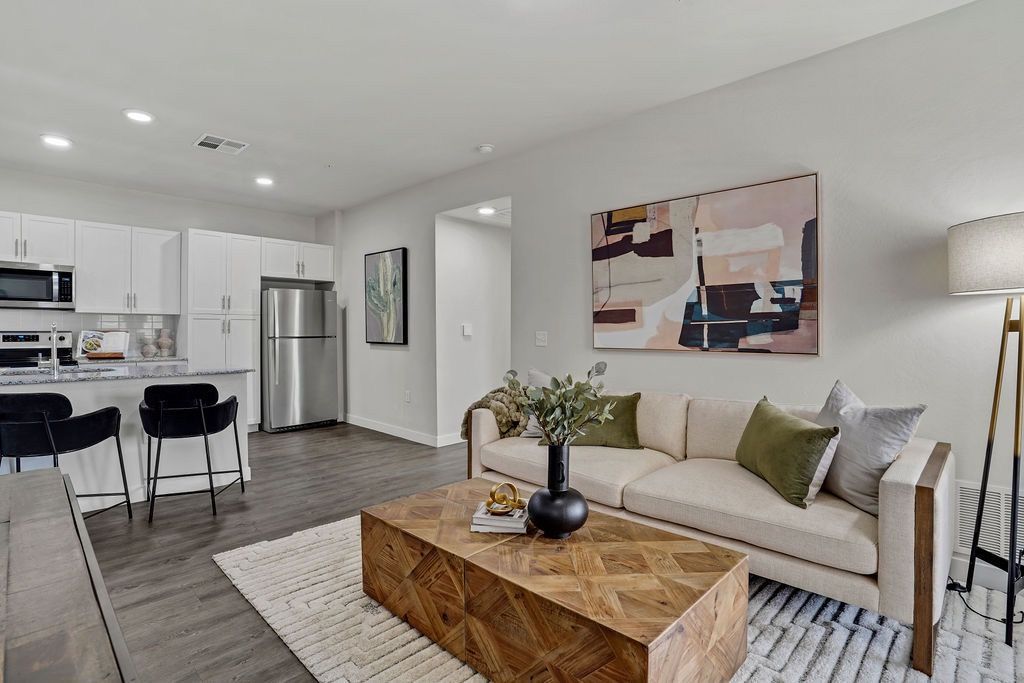 Open-concept living room and kitchen in a modern apartment with a sofa and stainless steel appliances.