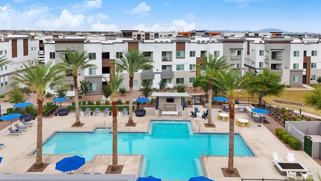 Aerial view of a community pool area with palm trees and lounge chairs.