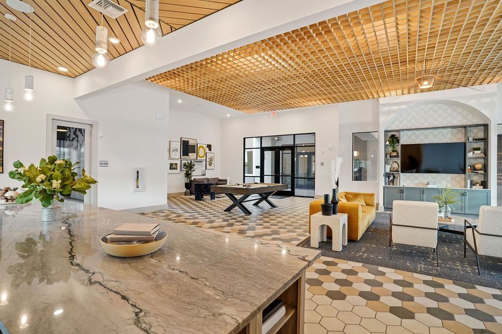 Modern apartment community lobby with marble counter, hex tile flooring, and seating area.
