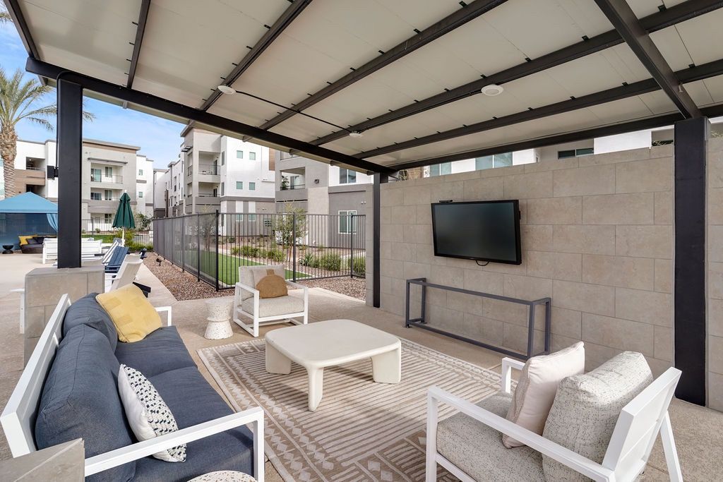 Outdoor covered lounge with seating and a wall-mounted TV.