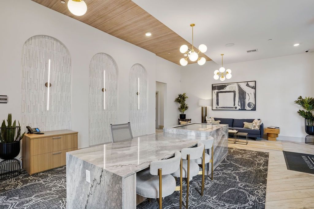 Modern apartment lobby with marble reception desk, pendant lights, and seating.