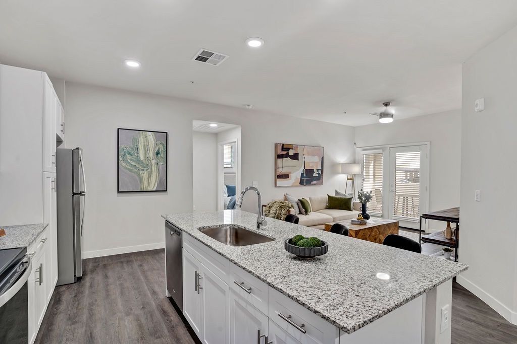 Open-concept kitchen with granite island, stainless steel appliances, and a view into the living area.