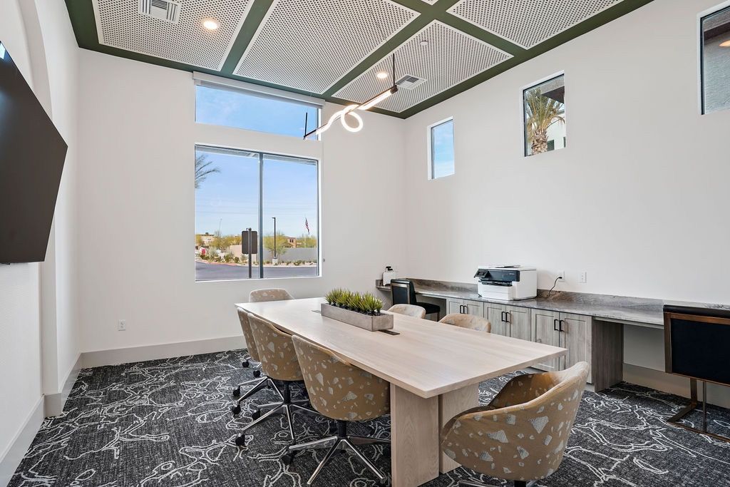 Modern community conference room with a long table, chairs, and a windowed wall.