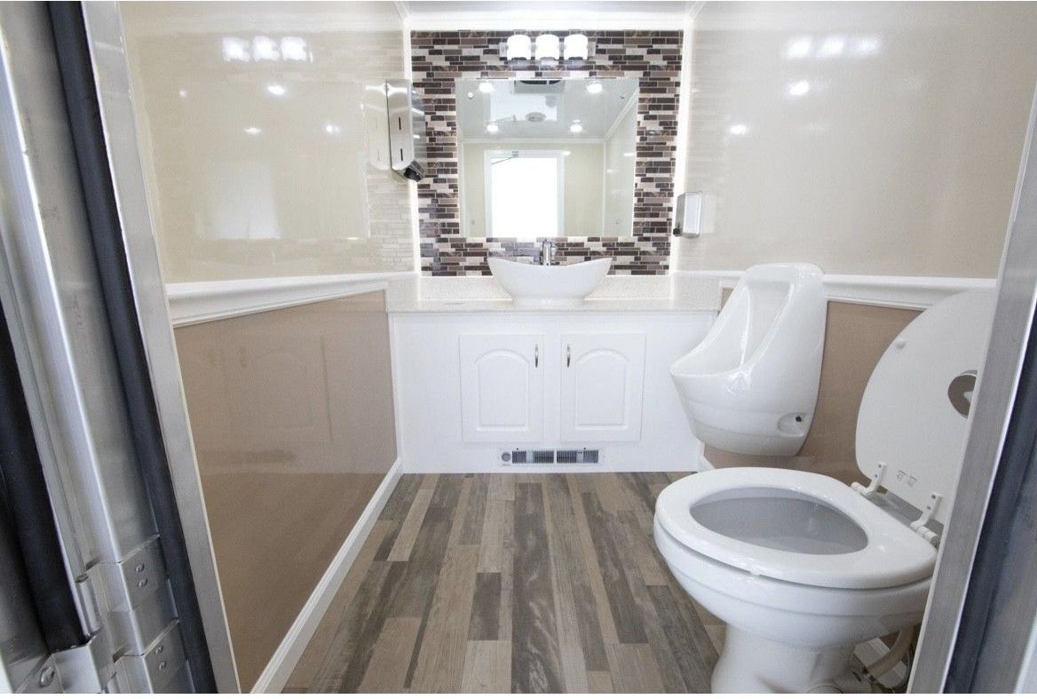 A bathroom with a toilet , sink , mirror and urinal.