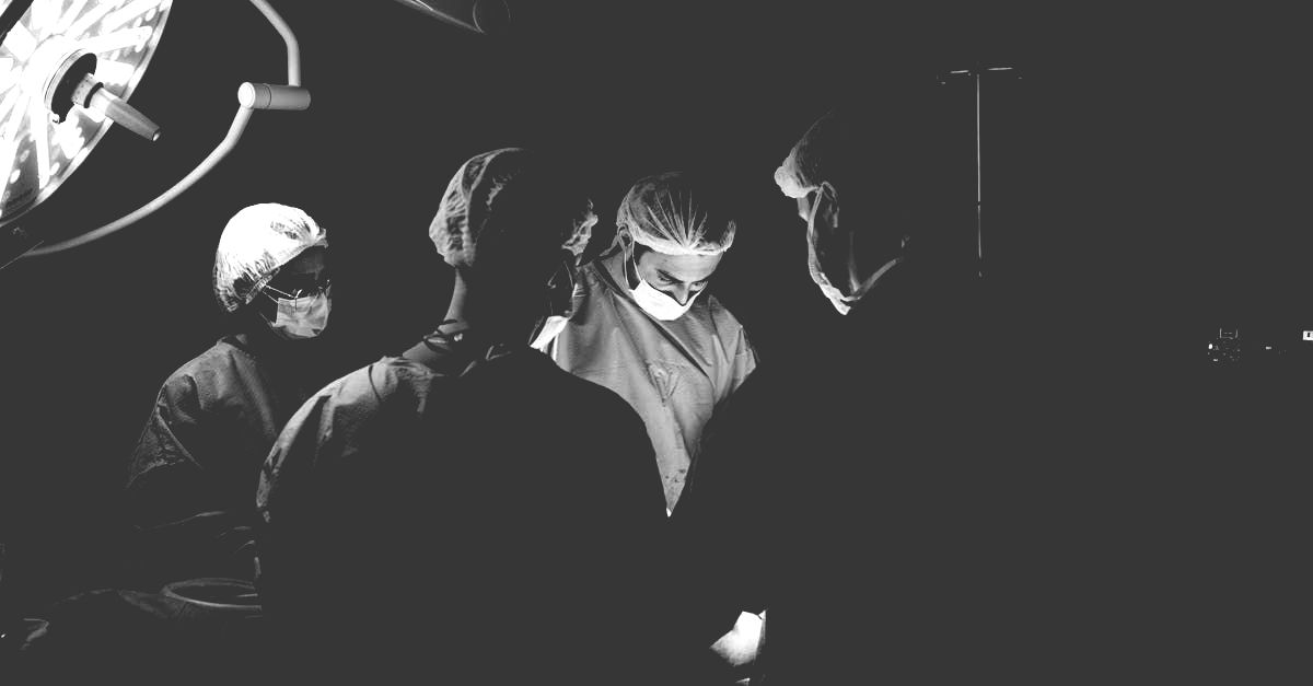 A group of surgeons are operating on a patient in an operating room.