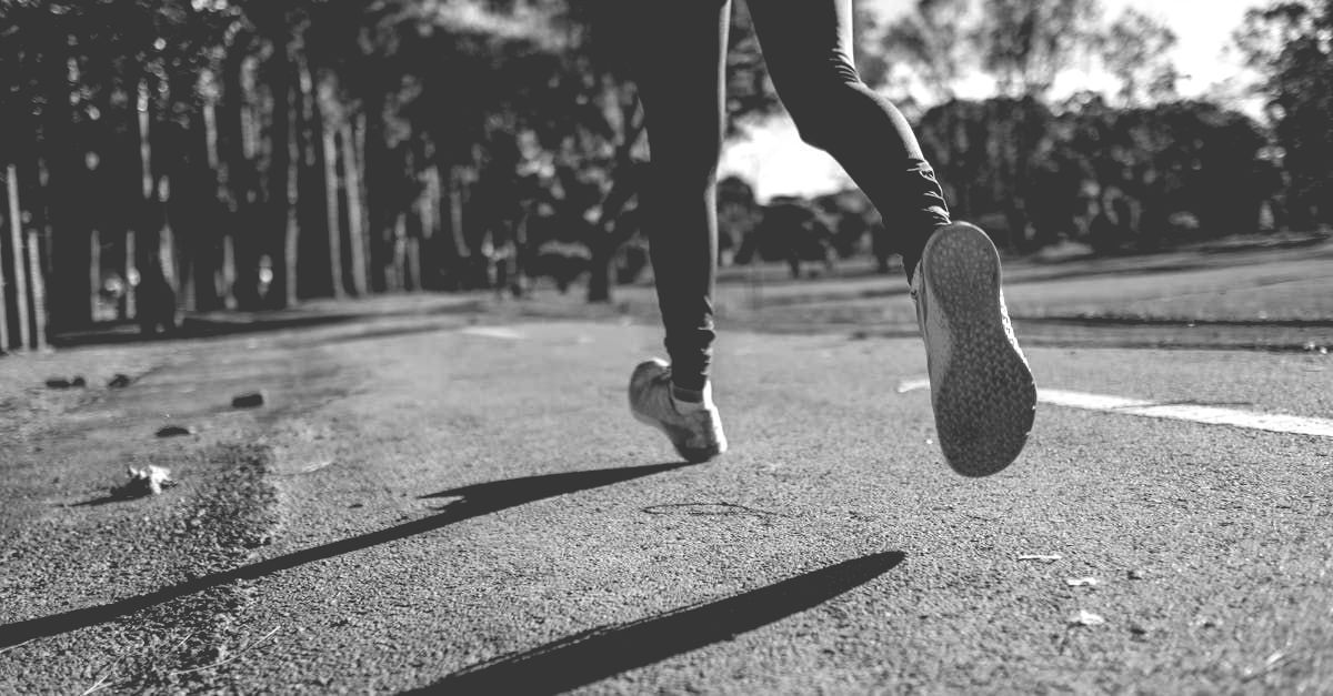 A black and white photo of a person running on a road.