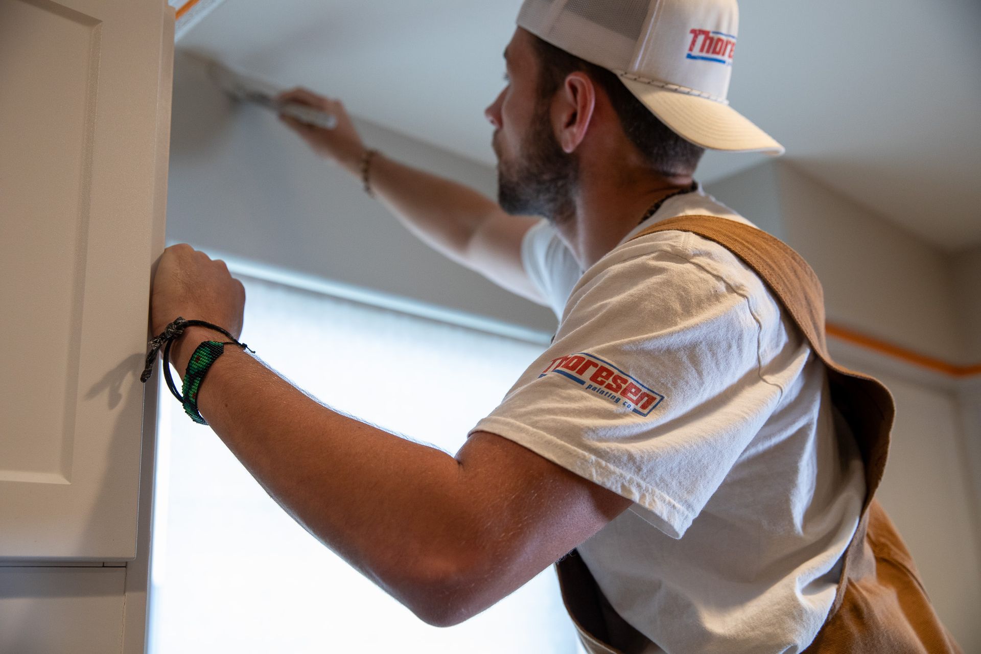 A man is painting a cabinet in a kitchen.