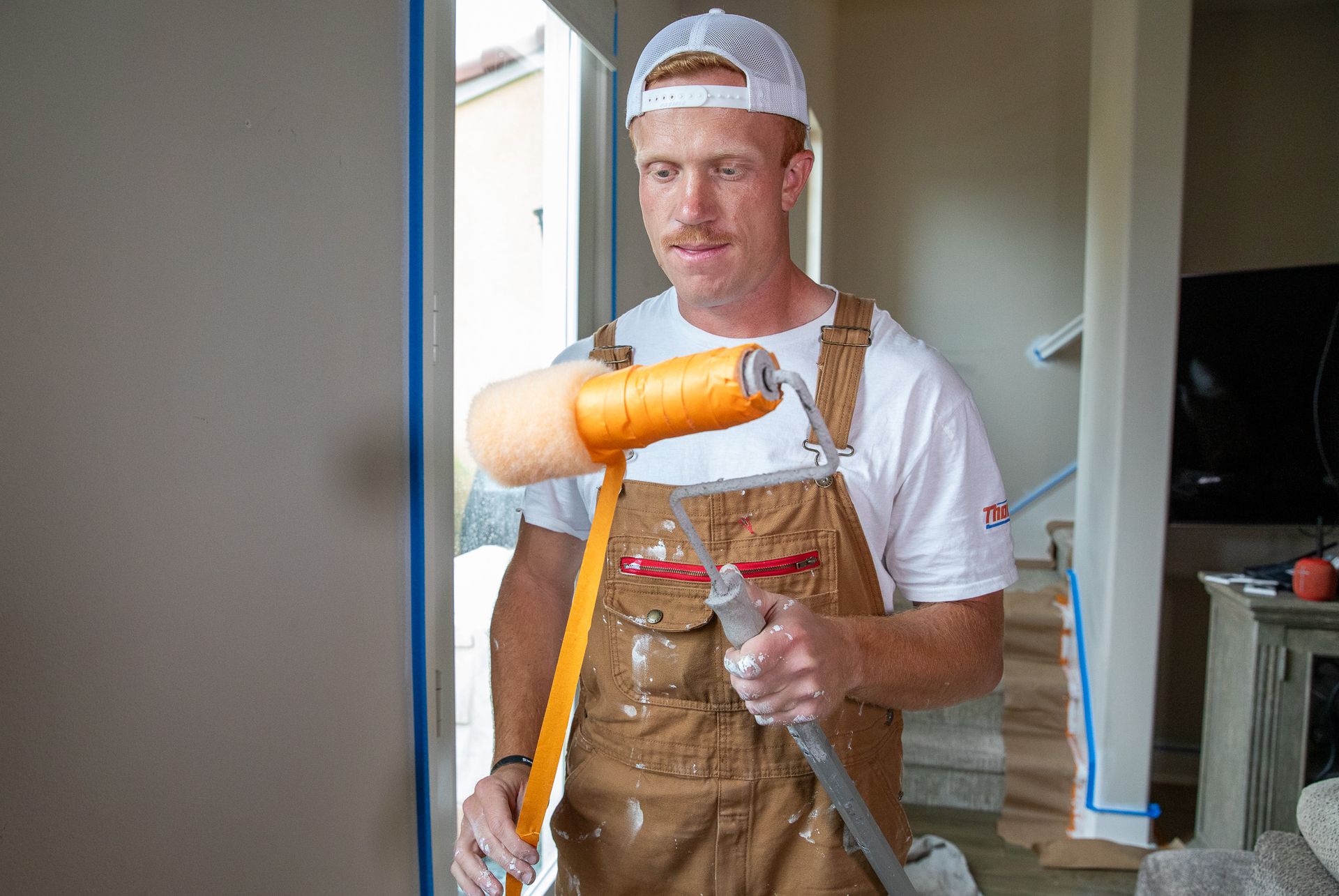 A man is painting a wall with a paint roller.