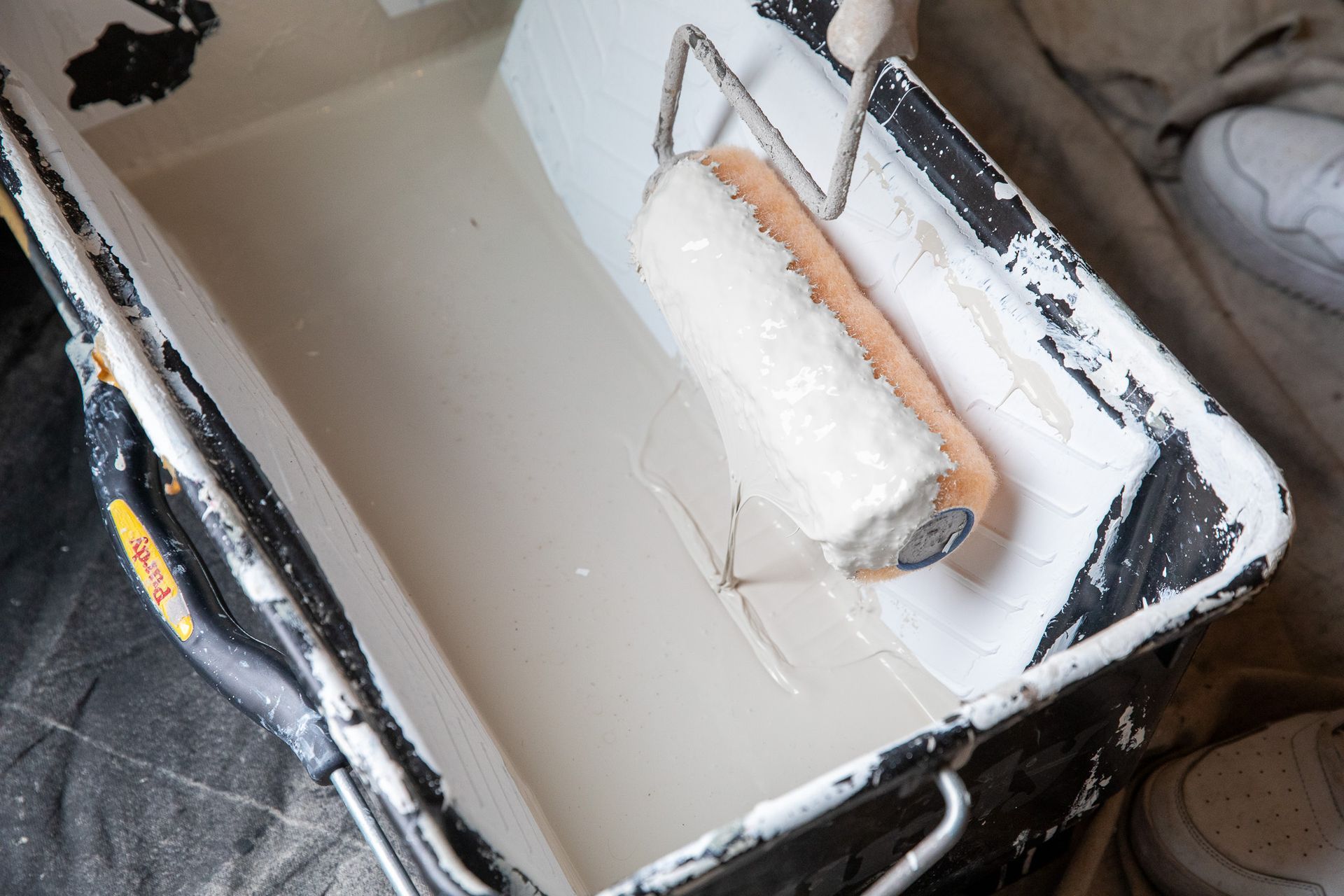 A paint roller is sitting in a bucket of paint