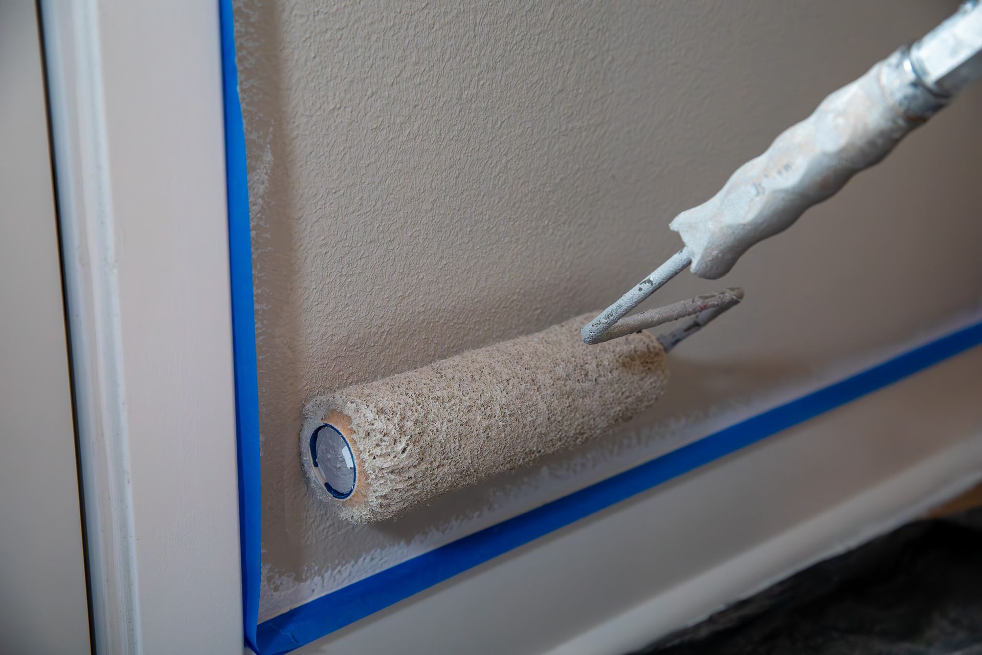 A person is painting a wall with a paint roller.