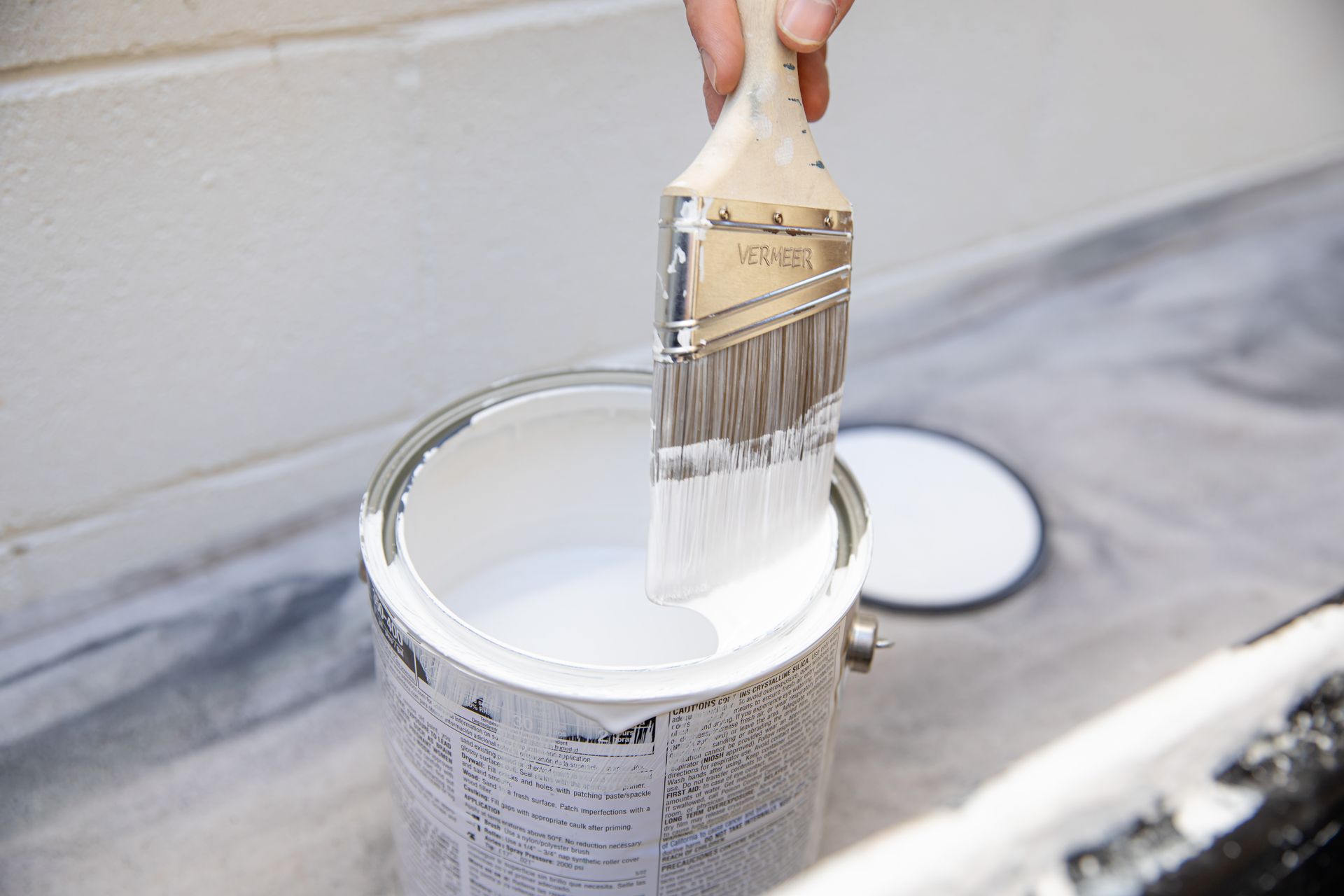 A person is painting a can of white paint with a brush.