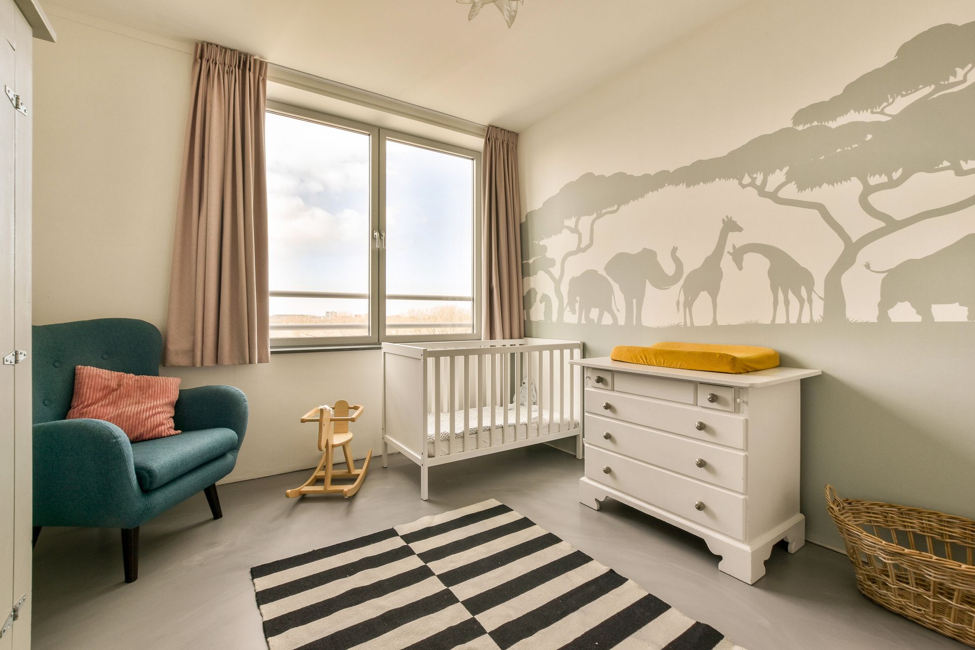 A baby 's room with a crib , dresser , chair and rug.