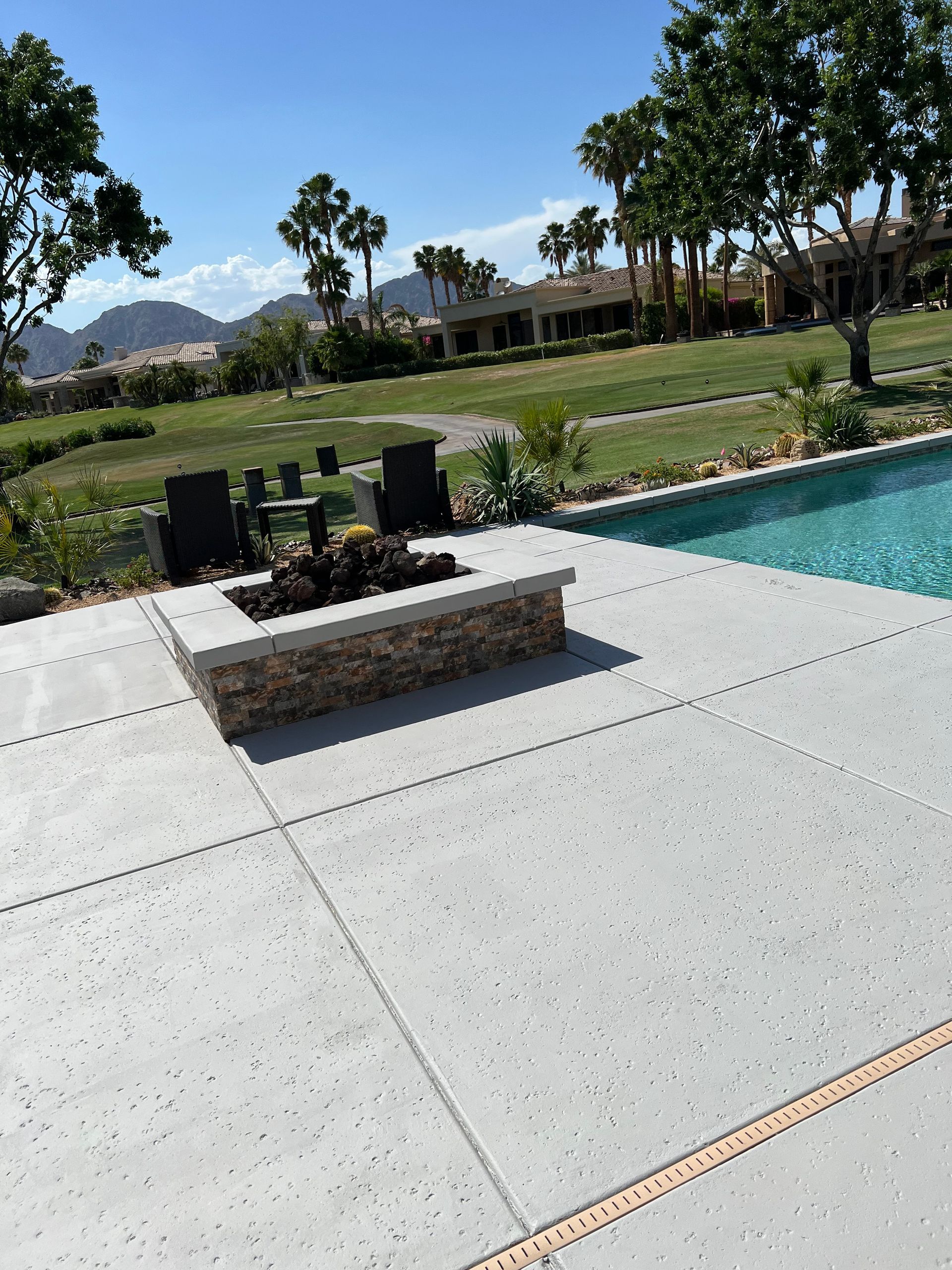 A fire pit sits on a patio next to a swimming pool
