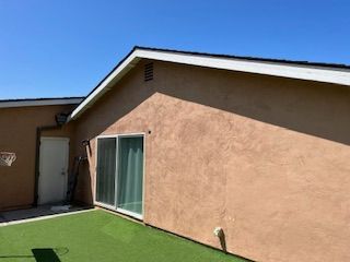 A house with a sliding glass door and a basketball hoop in the backyard.