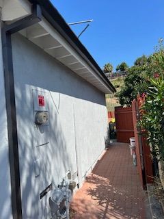 A house with a gutter on the side of it and a red fence.
