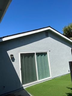 A house with a sliding glass door and a blue sky in the background.