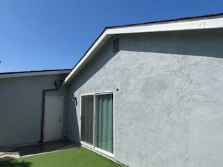 A house with a sliding glass door and a blue sky in the background.