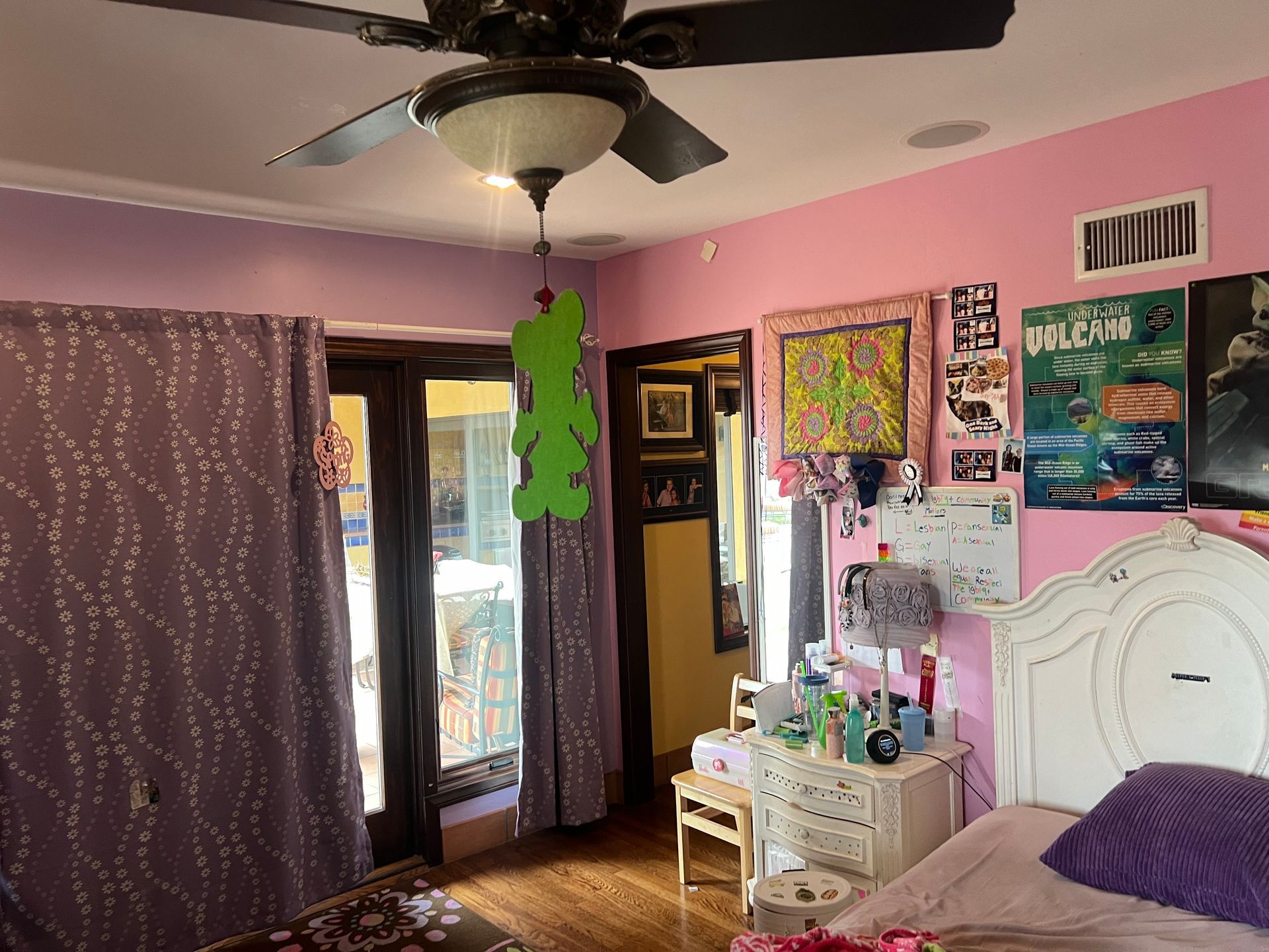 A bedroom with pink walls and a ceiling fan.
