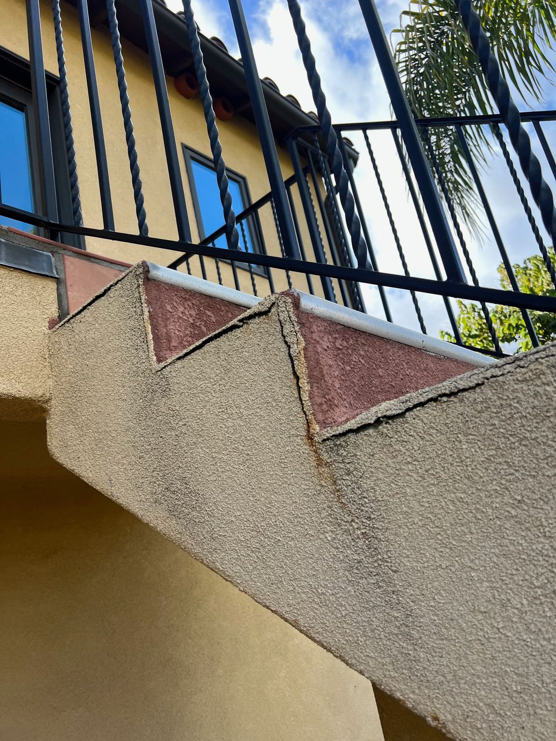 A set of stairs leading up to a balcony with a wrought iron railing.