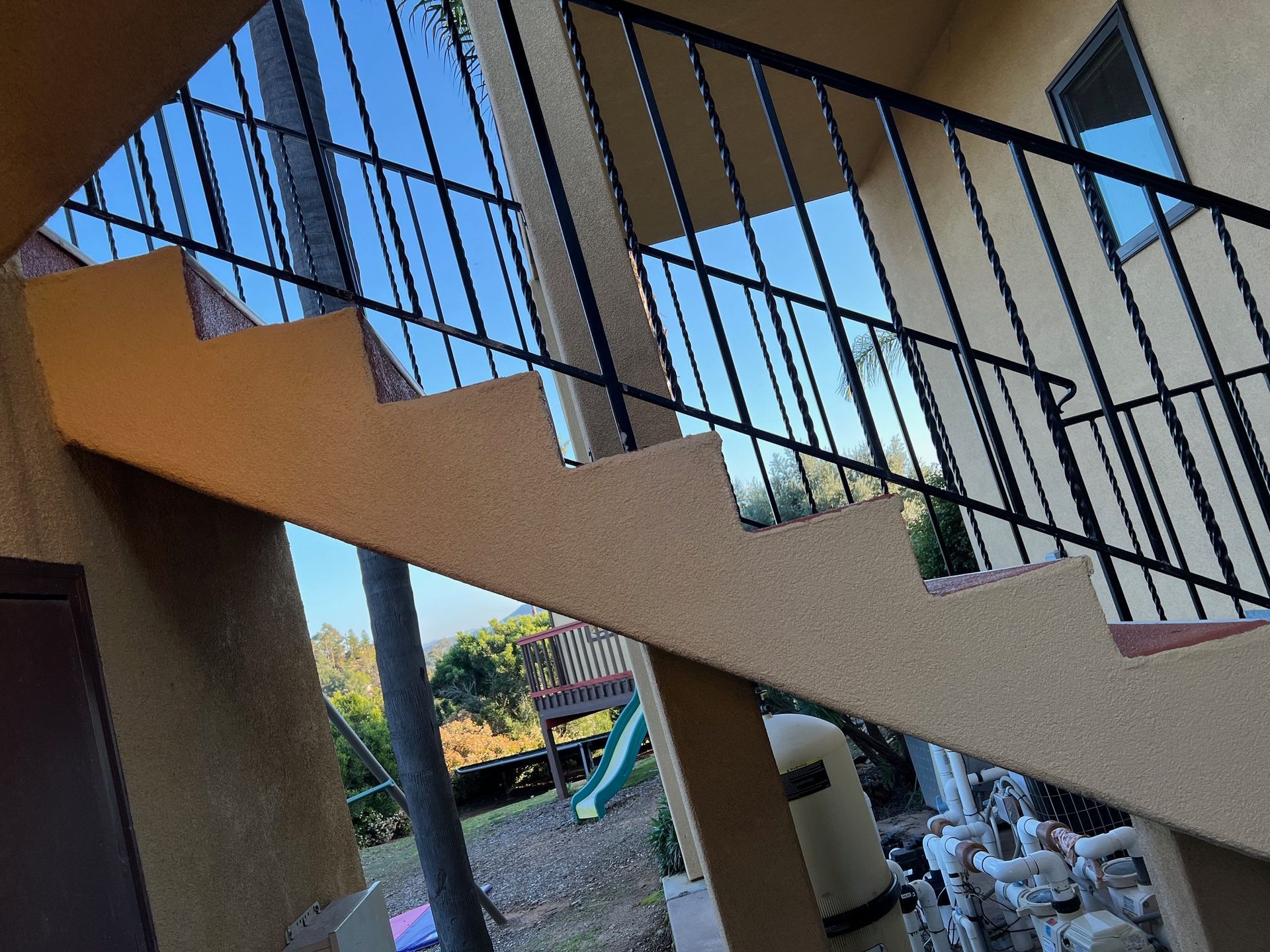 A set of stairs with a wrought iron railing leading up to the second floor of a building