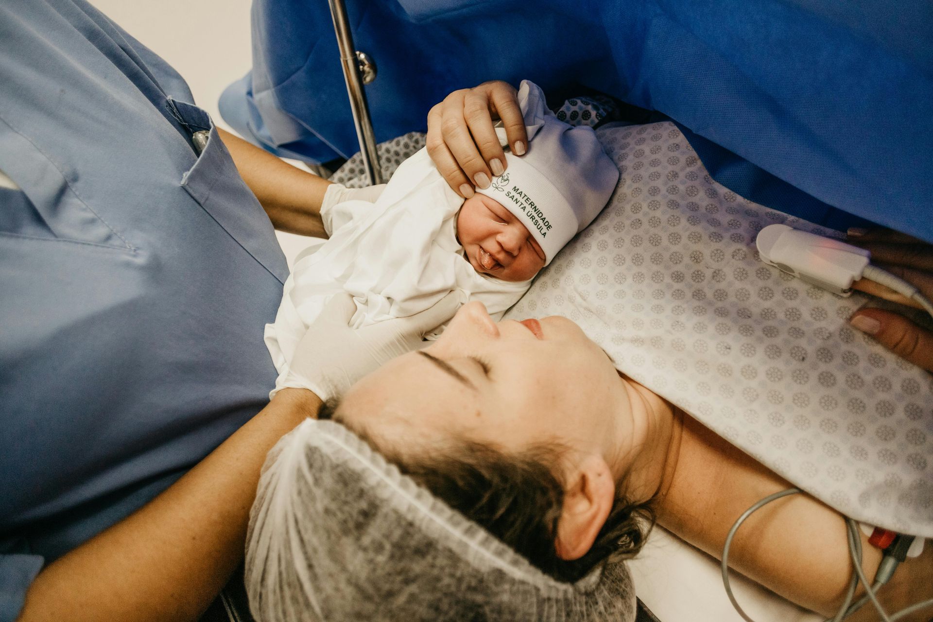 A woman is holding a newborn baby in a hospital bed.