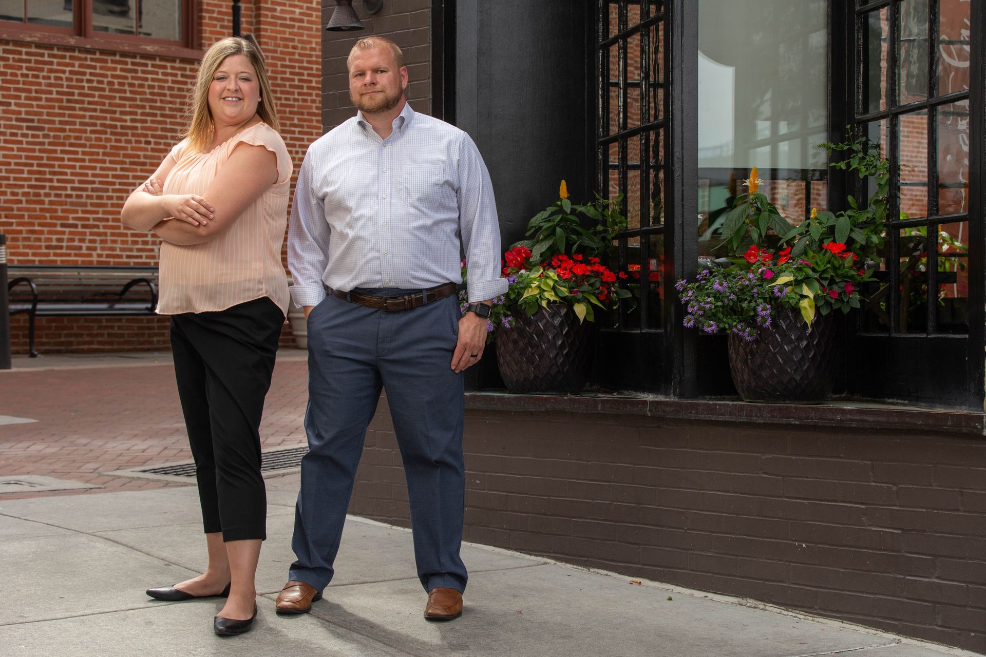 A man and a woman are standing next to each other on a sidewalk.