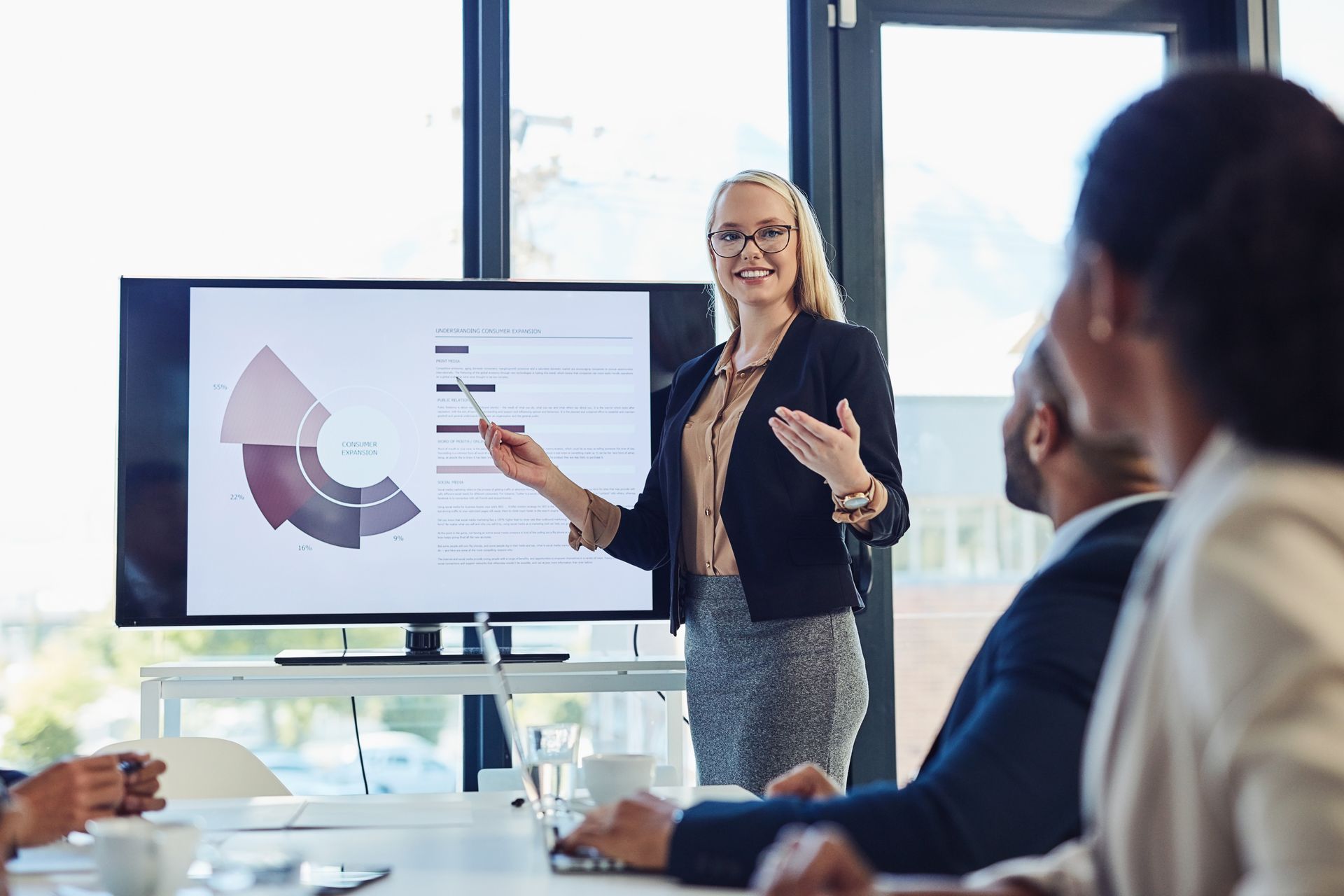 A woman is giving a presentation to a group of people in a conference room.